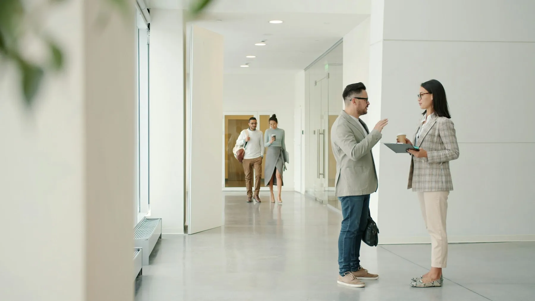 Two colleagues talking in a bright office corridor