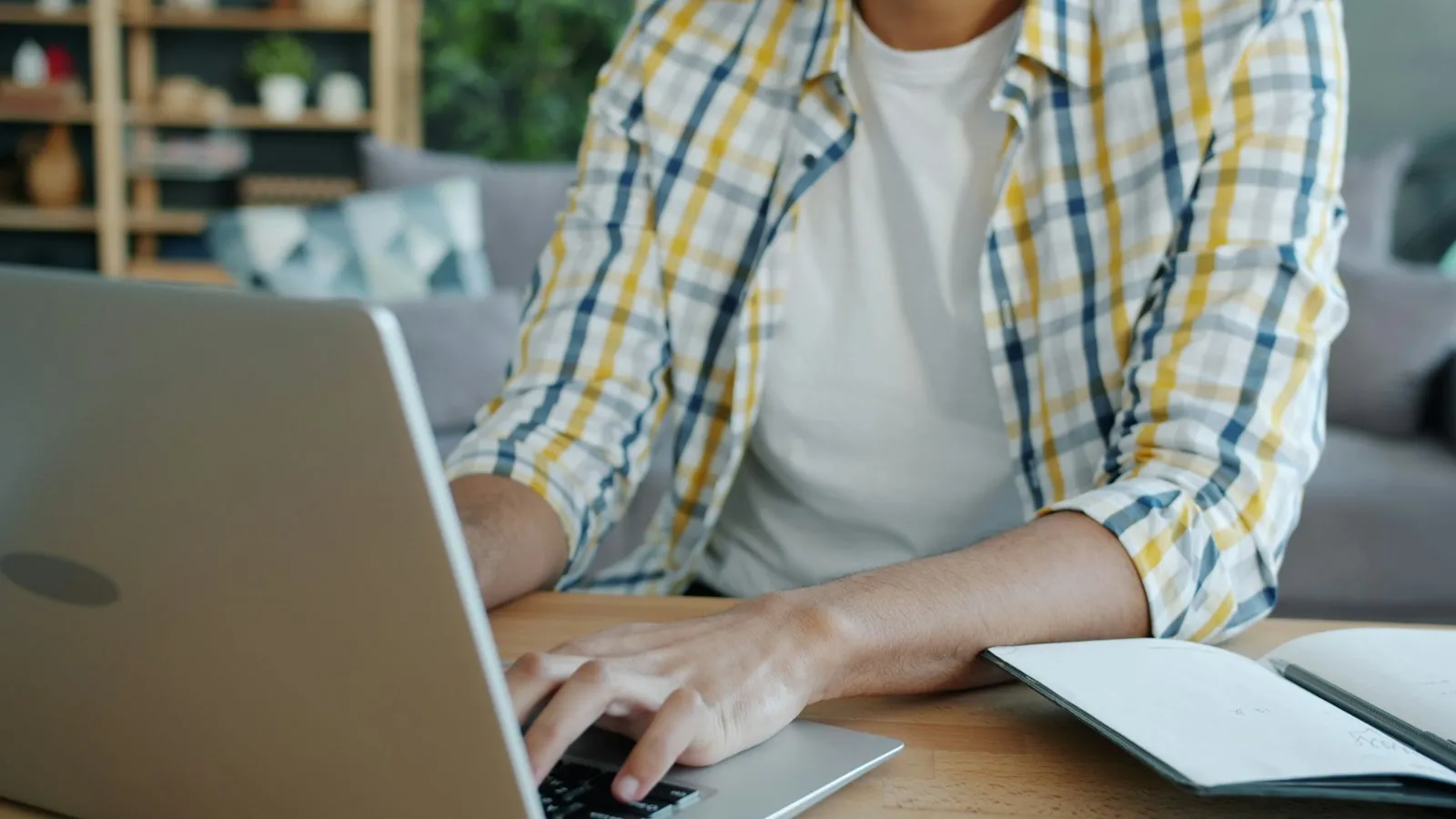 A student typing on a laptop while writing an application